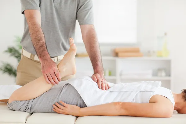 Chiropraktiker streckt Frau Bein aus — Stockfoto