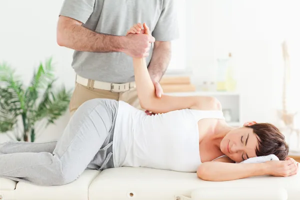 Chiropractor stretches a woman's arm — Stock Photo, Image