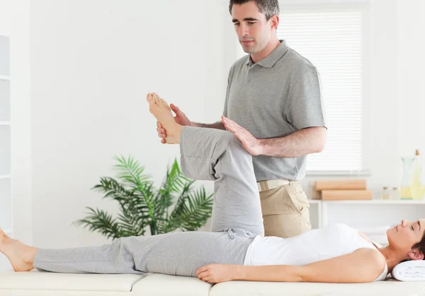 Quiropráctico estirando la pierna de un cliente — Foto de Stock