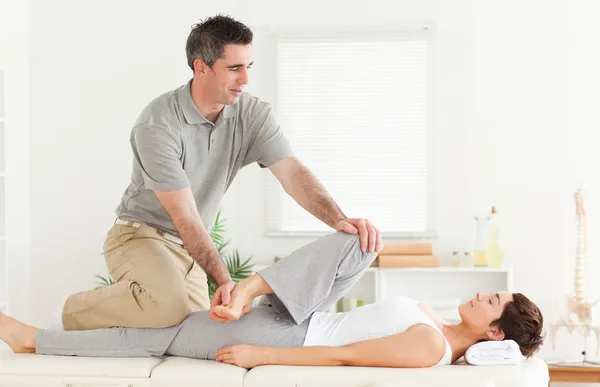Quiroprático esticando a perna de um cliente feminino — Fotografia de Stock