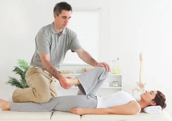 Chiropractor die zich uitstrekt van jonge vrouw been — Stockfoto