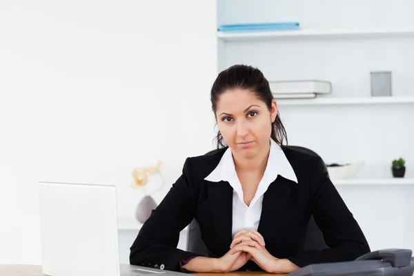 Серйозна бізнес-леді сидить на робочому місці — стокове фото