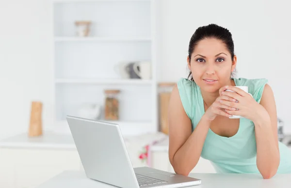 Mladá žena s kávou a laptop, při pohledu na fotoaparát — Stock fotografie