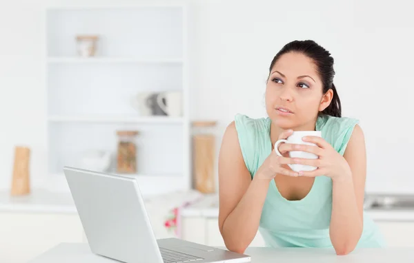 Mujer joven reflexiva con ordenador portátil y café — Foto de Stock