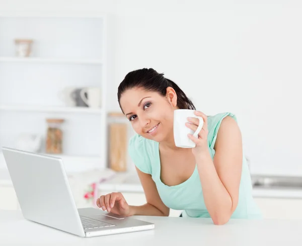 Giovane donna sorridente con caffè dal computer portatile — Foto Stock