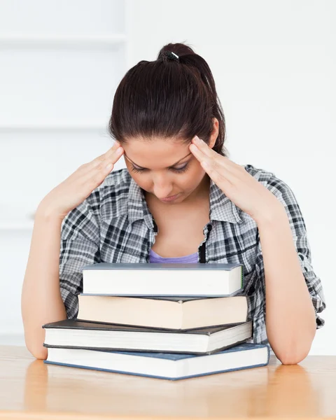 Frustrierte junge Studentin lehnt sich an Bücher — Stockfoto