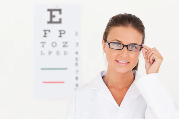 Brunette eye specialist wearing glasses looking into the camera — Stock Photo, Image
