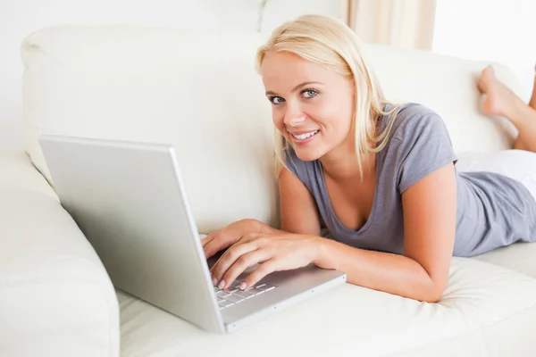 Liggande kvinna använder en bärbar dator — Stockfoto