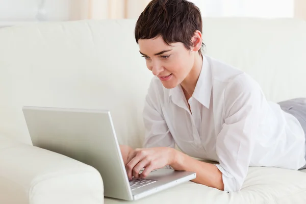 Woman lying on a sofa with a laptop Royalty Free Stock Images