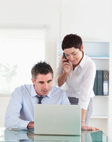 Portrait of a woman making a phone call while her colleague is l — Stock Photo, Image