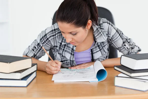 Young student writing into her exercise book — Stock Photo, Image