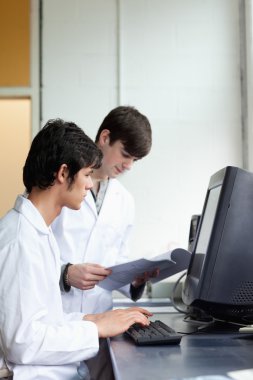 Male scientists using a monitor clipart