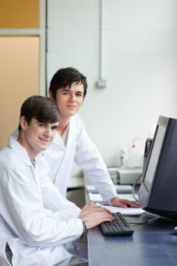 Portrait of scientists posing with a monitor clipart