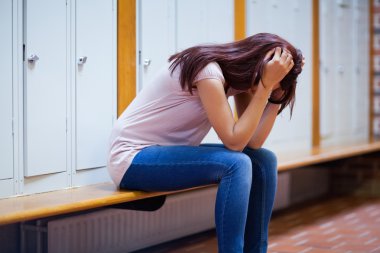 Sad student sitting on a bench clipart