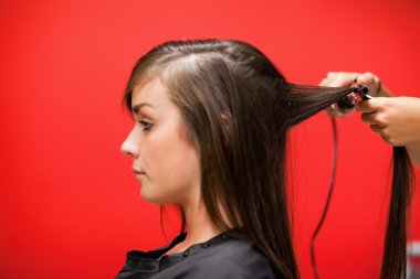 Woman having her hair straightened clipart