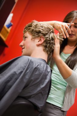 Portrait of a serious woman cutting a man's hair clipart