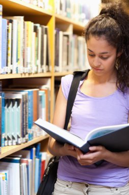 Portrait of a serious female student reading a book clipart