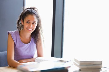 Smiling student sitting with a book clipart