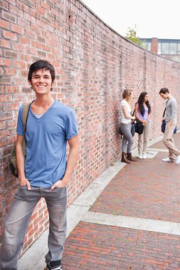 Portrait of a student posing while his friends are talking clipart