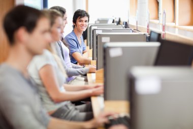 Young fellow students in an IT room clipart