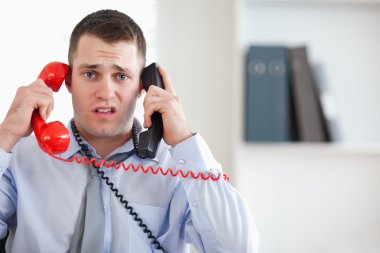 Close up of businessman unable to cope with the telephone clipart