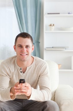 Portrait of a man sending text messages while sitting on a sofa clipart