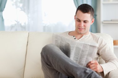 Young man reading a newspaper clipart