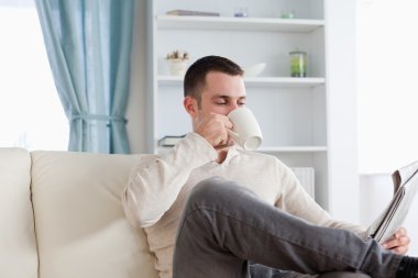 Young man having a coffee while reading the news clipart