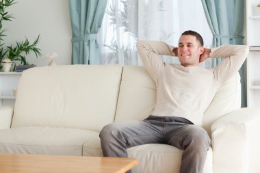 Happy man relaxing on a couch clipart