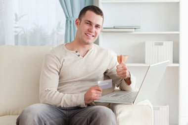 Happy man shopping online with the thumb up clipart