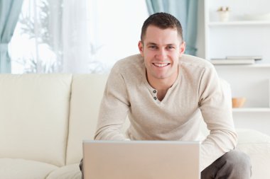 Smiling young man using a notebook clipart