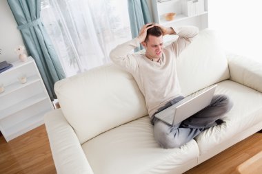 Unhappy man using a notebook clipart