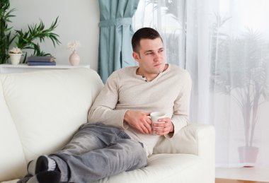 Pensive man holding a cup of coffee clipart