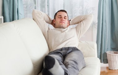 Young man resting on a sofa clipart