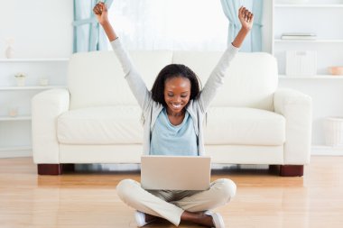 Woman stretching while sitting on the floor working on her noteb clipart