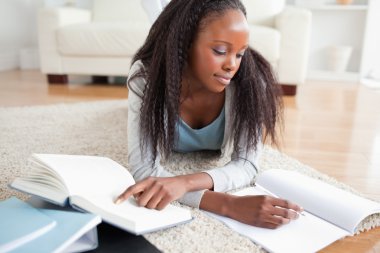 Woman lying on the floor doing a book review clipart