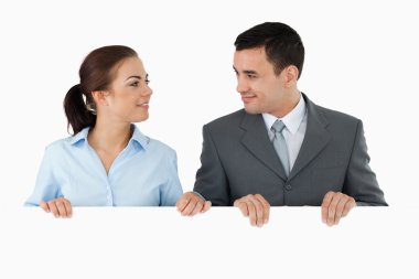 Business partners looking at each other while holding sign toget clipart