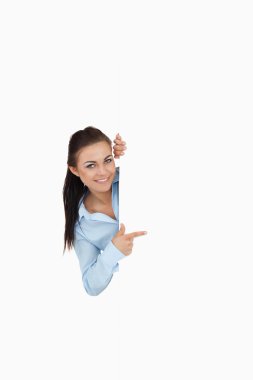 Smiling businesswoman looking around the corner while pointing clipart