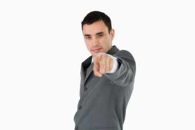 Side view of young businessman pointing towards camera clipart