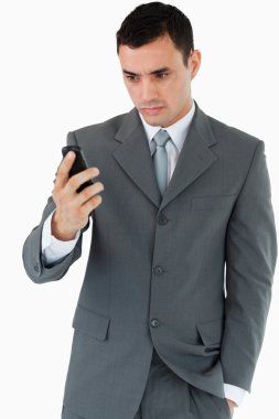 Serious looking businessman looking at his cellphone clipart