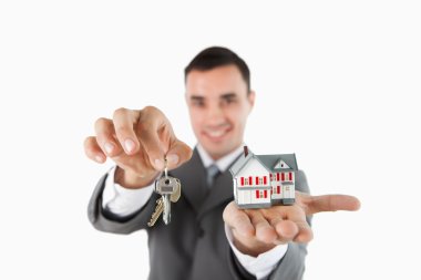 Close up of keys and miniature house being held by male estate a clipart