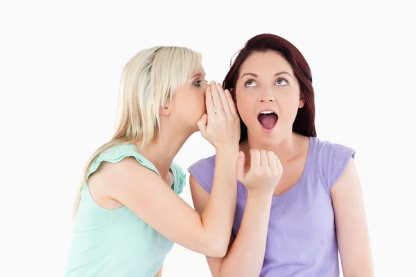 Portrait of a blond woman telling her friend a secret — Stock Photo, Image