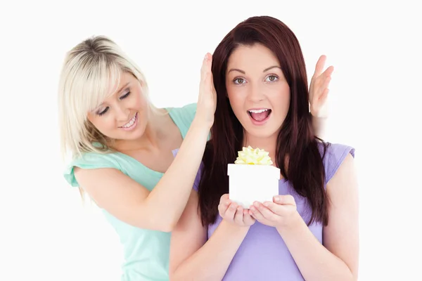 Young woman giving a gift to her friend — Stock Photo, Image
