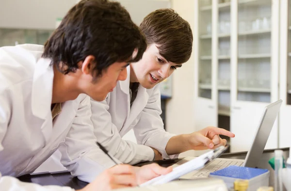 Smiling chemistry students writing a report — Stock Photo, Image