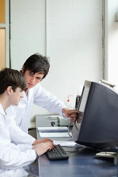 Phisician pointing at something on a monitor to his student — Stock Photo, Image