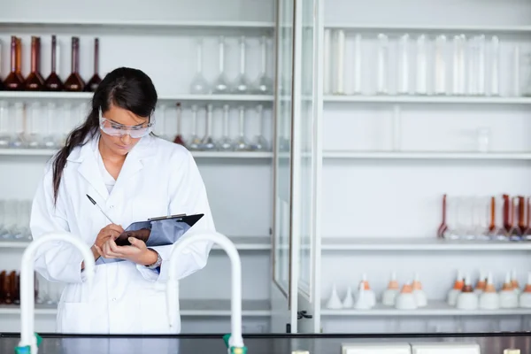 Focused female scientist writing on a clipboard — Stock Photo, Image
