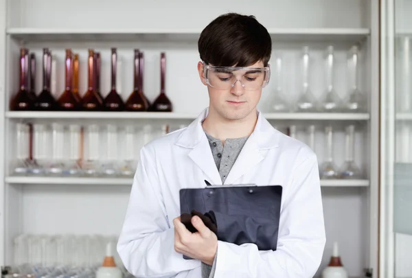 Científico masculino escribiendo en un portapapeles —  Fotos de Stock