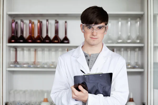 Male science student writing on a clipboard — Stock Photo, Image