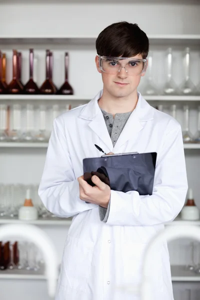 Porträt eines männlichen Studenten der Naturwissenschaften, der auf ein Klemmbrett schreibt — Stockfoto