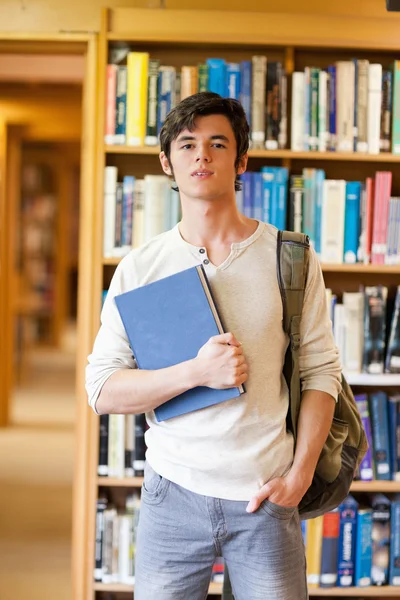 Улыбающийся студент позирует с книгой — стоковое фото